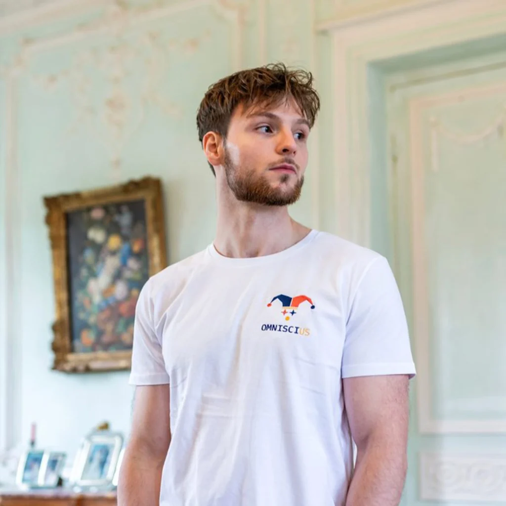 Photo du t-shirt blanc brodé avec le Joker Omniscius. Porté par Romain