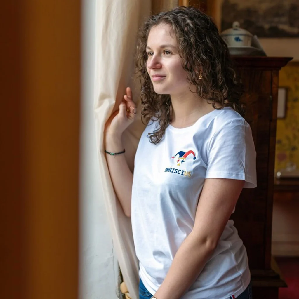 Photo du t-shirt blanc brodé avec le Joker Omniscius. Porté par Inès